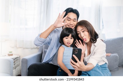 Portrait of happy asian family with toddler girl child use smartphone selfie say hi virtual in living room. Happy live online influencer blogger. Technology connected people family lifestyle concept - Powered by Shutterstock