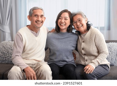 portrait happy asian family,older adult father and mother with young adult daughter sitting on couch,hugging together,smiling and looking at camera  - Powered by Shutterstock