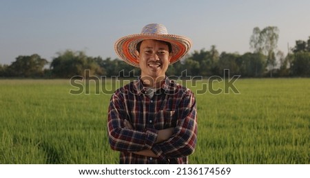 Portrait Happy Asian Farmer arms crossed smiling and looking at camera green paddy field on background.