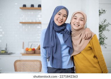 Portrait of happy Asian friends muslim woman with hijab dress smiling and hugging together in the modern home. - Powered by Shutterstock