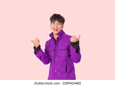 Portrait Of Happy Asian Handsome Young Man In Fashionable Jacket Clothes Standing Smiling With Thumbs Up And Look At Camera Isolated On Pink Background. Attractive Male Model Lifestyle Face Gesture. 