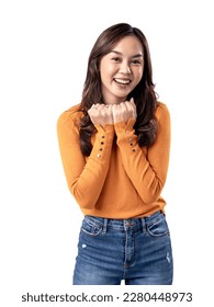 A portrait of a happy Asian Indonesian woman wearing an orange sweater and clenching both hands under her chin, isolated on a white background - Shutterstock ID 2280448973
