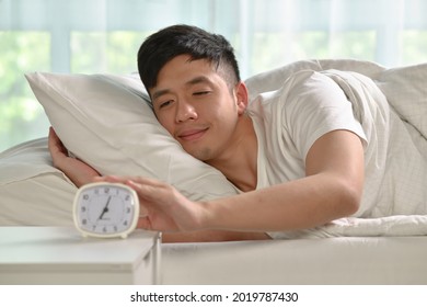 Portrait of happy Asian man waking up in bed in the morning