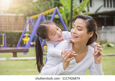 Portrait Of Happy Asian Mother And Daughter. Asian Woman And Little Toddler Girl Cuddling And Hugging In The Playground Park. Happy Family Green Spring Or Summer Mother’s Day Together Concept