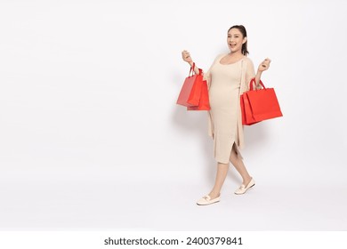 Portrait of Happy Asian pregnant woman holding red shopping bags isolated on white background, Motherhood and Pregnancy Concept, Full body composition - Powered by Shutterstock