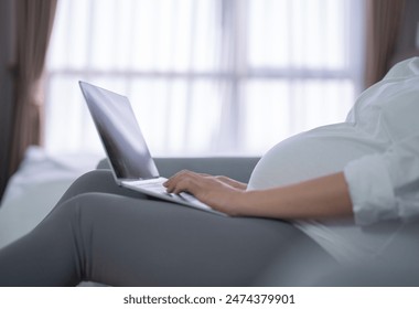 A portrait of happy Asian pregnant woman using, working online with computer laptop notebook tablet device with screen in bedroom at home. Having a baby. Family people lifestyle. Mom love. - Powered by Shutterstock