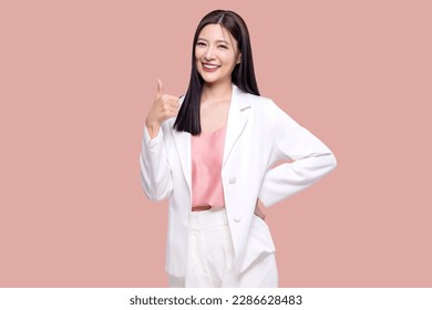 Portrait happy Asian woman shows thumb up and looking at the camera on pink background. - Shutterstock ID 2286628483