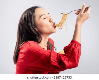 A portrait of a happy Asian woman wearing a red shirt, eating noodles. Isolated against a white background. - Powered by Shutterstock