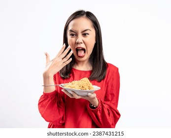 A portrait of a happy Asian woman wearing a red shirt, eating noodles, and feeling a bit spicy. Isolated against a white background.