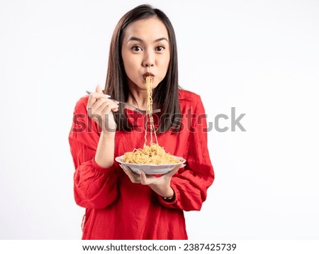 A portrait of a happy Asian woman wearing a red shirt, eating noodles. Isolated against a white background.