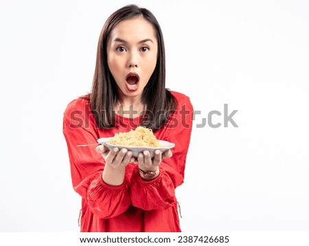 A portrait of a happy Asian woman wearing a red shirt,  presenting noodles, and about to eat them. Isolated against a white background.