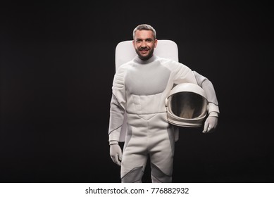 Portrait of happy astronaut is holding helmet while standing in white protective suit. He is looking at camera with joy. Isolated background with copy space in left side. Spaceman concept