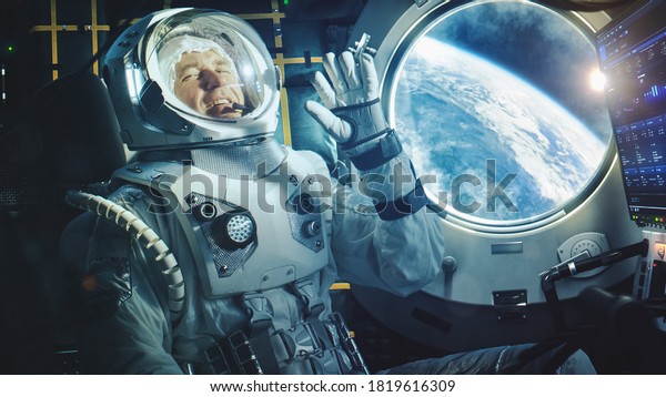 Portrait of a Happy Astronaut on a Space Ship In\
Orbit. Cosmonaut in a Futuristic Space Suit is Full of Joy and is\
Waving Hand on a Video Call. VFX Graphics Shot from the\
International Space\
Station.