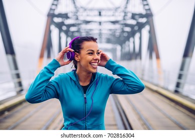 Portrait Of A Happy Athlete Woman Putting On Earphones.