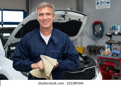 Portrait Of A Happy Auto Mechanic Cleaning Hands With Cloth - Powered by Shutterstock