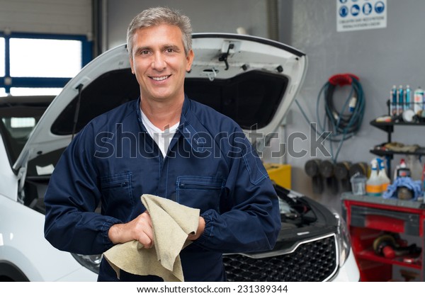 Portrait Of A Happy Auto Mechanic Cleaning Hands\
With Cloth