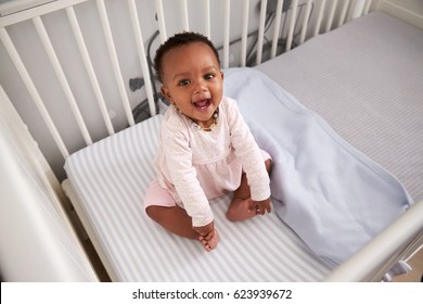 Portrait Of Happy Baby Girl Playing In Nursery Cot