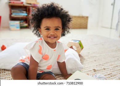 Portrait Of Happy Baby Girl Playing With Toys In Playroom