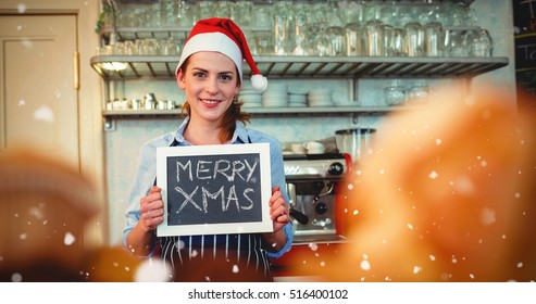 Portrait of happy barista holding Christmas at cafe against snow falling - Powered by Shutterstock