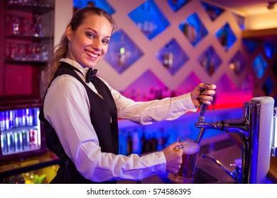 Portrait of happy barmaid pouring beer in glass at bar counter - Powered by Shutterstock