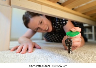 Portrait of a happy beautiful adult woman (female age 30-40) finding home keys under the bed in a domestic house bedroom. Real people. Copy space - Shutterstock ID 1919307119