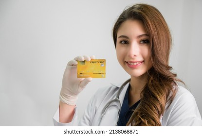 Portrait Of Happy Beautiful Asian Woman Doctor In White Gown With Stethoscope Standing Hold Credit Card In Office At Hospital. Young Female Medical Smile With Show Card For Health Insurance In Clinic.