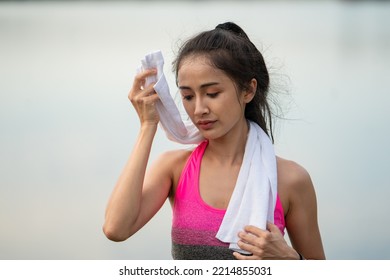 Portrait Of A Happy Beautiful Asian Woman Using A White Towel To Wipe Sweat From Her Face After Exercise.