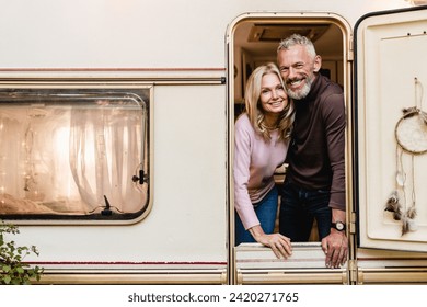 Portrait of happy beautiful caucasian senior couple traveling together standing on the porch of their motorhome trailer camper van decorated with dreamcatcher - Powered by Shutterstock