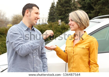 Portrait of happy beautiful couple with car key, standing near the car