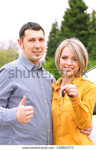 Portrait of happy beautiful couple with car key,\
standing near the car