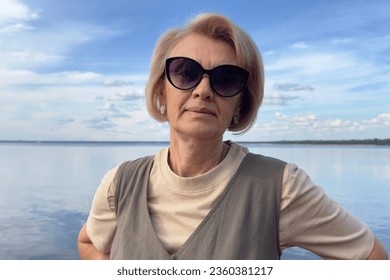 Portrait of happy beautiful elderly senior woman in sunglasses enjoy summer sunny day at beach, sea  - Powered by Shutterstock