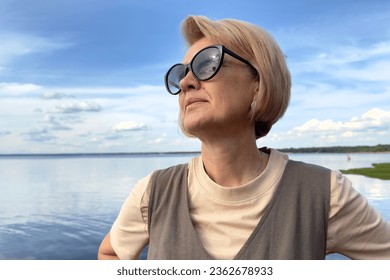 Portrait of happy beautiful elderly senior woman in sunglasses enjoy summer sunny day at beach, sea  - Powered by Shutterstock