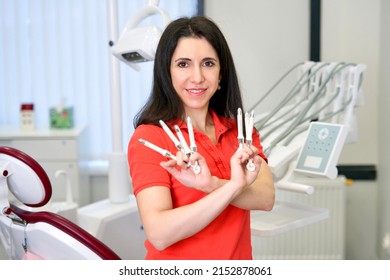 Portrait Of Happy Beautiful Female Doctor, Attractive Pretty Caucasian Armenian Ethnic Dentist Standing In Dental Office At Clinic, Smiling, Looking At Camera, Making Filling Material Set