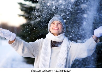 Portrait of happy beautiful girl, young joyful positive woman walking playing with snow, snowflakes, having fun outdoors in winter clothes, hat and scarf, smiling. Winter season, weather 