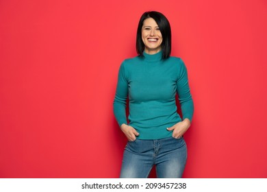 Portrait Of Happy Beautiful Middle Aged Woman With Black Hair In Blue Blouse And Jeans . Indoor Studio Shot Isolated On Red