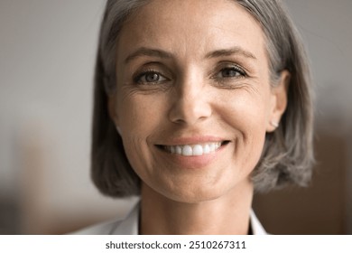 Portrait of happy beautiful middle-aged 50s woman with short haircut looking at camera, close up cropped face view on abstract background. Rejuvenating skin care products, dental clinic services ad - Powered by Shutterstock