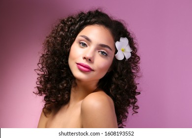 Portrait Of Happy Beautiful Woman With Long Bouncy Curls Hairstyle And Professional Make Up On, Posing Over Isolated Purple Background. Fashion Shot Of Young Gorgeous Female. Close Up, Copy Space.