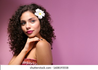 Portrait Of Happy Beautiful Woman With Long Bouncy Curls Hairstyle And Professional Make Up On, Posing Over Isolated Purple Background. Fashion Shot Of Young Gorgeous Female. Close Up, Copy Space.