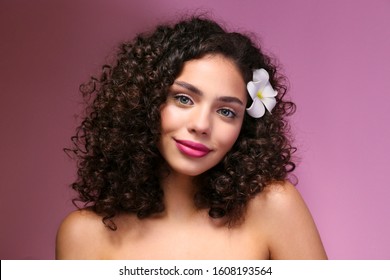 Portrait Of Happy Beautiful Woman With Long Bouncy Curls Hairstyle And Professional Make Up On, Posing Over Isolated Purple Background. Fashion Shot Of Young Gorgeous Female. Close Up, Copy Space.