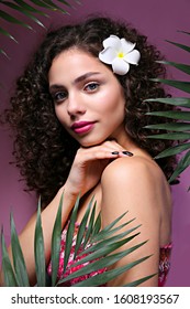 Portrait Of Happy Beautiful Woman With Long Bouncy Curls Hairstyle And Professional Make Up On, Posing Over Isolated Purple Background. Fashion Shot Of Young Gorgeous Female. Close Up, Copy Space.