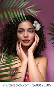 Portrait Of Happy Beautiful Woman With Long Bouncy Curls Hairstyle And Professional Make Up On, Posing Over Isolated Purple Background. Fashion Shot Of Young Gorgeous Female. Close Up, Copy Space.