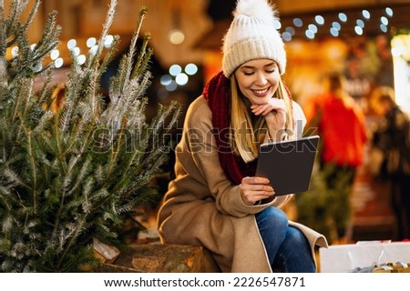 Portrait of happy beautiful young woman enjoying holiday and buy christmas tree on decorated market
