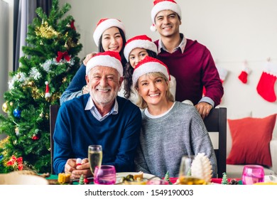 Portrait Of Happy Big Family Celebrating Santa Hats Having Fun And Lunch Together Look At Camera And Enjoying Spending Time Together In Christmas Time At Home