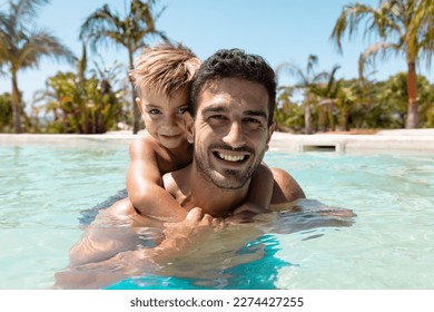 Portrait of happy biracial father and son playing together in swimming pool. Spending quality time, lifestyle, family, summertime and vacation concept. - Powered by Shutterstock