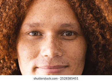 Portrait of happy biracial man with curly red hair and freckles smiling. Wellbeing, lifestyle and domestic life, unaltered. - Powered by Shutterstock