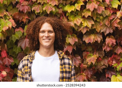 Portrait of happy biracial man with red curly hair standing in autumn garden smiling, copy space. Free time, lifestyle, nature and wellbeing, unaltered. - Powered by Shutterstock