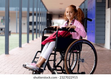 Portrait of happy biracial schoolgirl in wheelchair, smiling in school corridor. Education, childhood, elementary school, inclusivity and learning concept. - Powered by Shutterstock