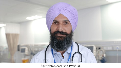 Portrait of happy biracial sikh male doctor in turban looking at camera at hospital, in slow motion. Hospital, medicine and healthcare. - Powered by Shutterstock