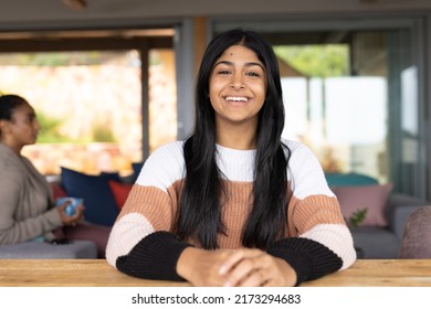 Portrait Of Happy Biracial Teenage Girl Sitting At Table While Mother With Cup Sitting In Background. Long Hair, Family, Love, Togetherness, Childhood, Coffee, Relaxing, Lifestyle And Home Concept.