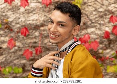 Portrait of happy biracial transgender man looking at camera, with rocks and leaves in background. Gender, fashion and lifestyle, unaltered. - Powered by Shutterstock